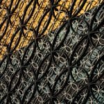 a close up of a metal fence with a building in the background