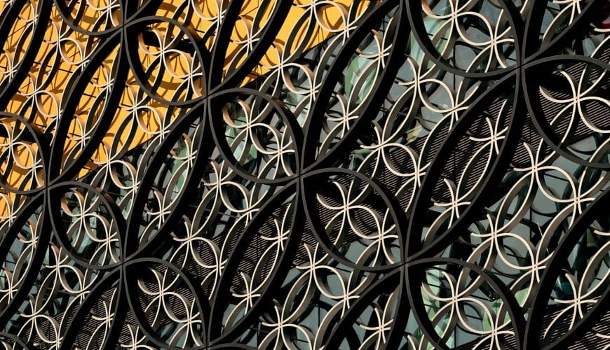 a close up of a metal fence with a building in the background