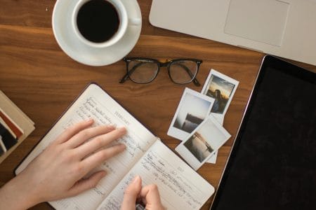 person holding ballpoint pen writing on notebook