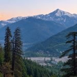 Manali in October: wide mountain range with snow on distant high peaks above Bashisht valley and pine forests.