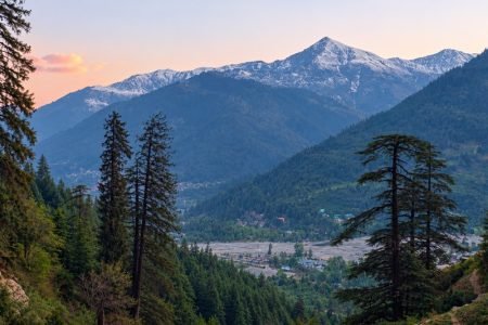Manali in October: wide mountain range with snow on distant high peaks above Bashisht valley and pine forests.