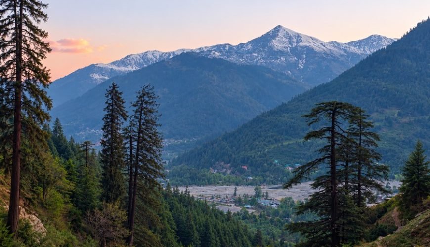 Manali in October: wide mountain range with snow on distant high peaks above Bashisht valley and pine forests.