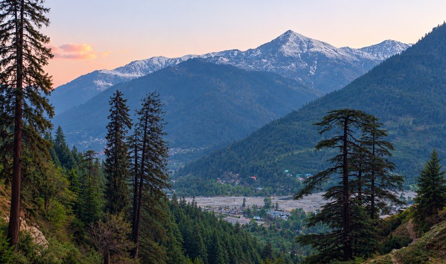 Manali in October: wide mountain range with snow on distant high peaks above Bashisht valley and pine forests.